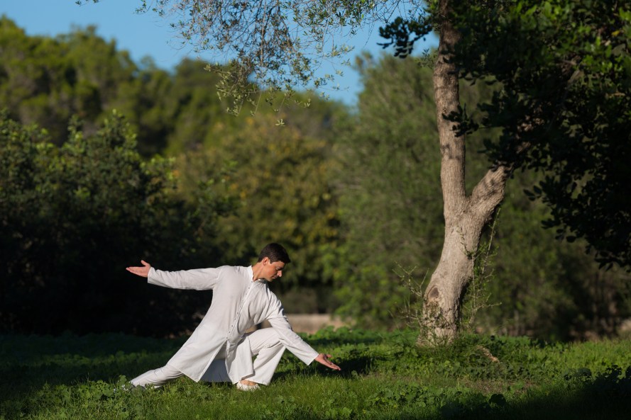 man practicing Tai-Chi outdoors in the park