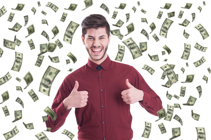 Excited businessman raising thumbs up and standing under money r