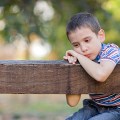 orphan, unhappy boy sitting on a park bench and crying