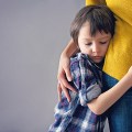 Sad little child, boy, hugging his mother at home