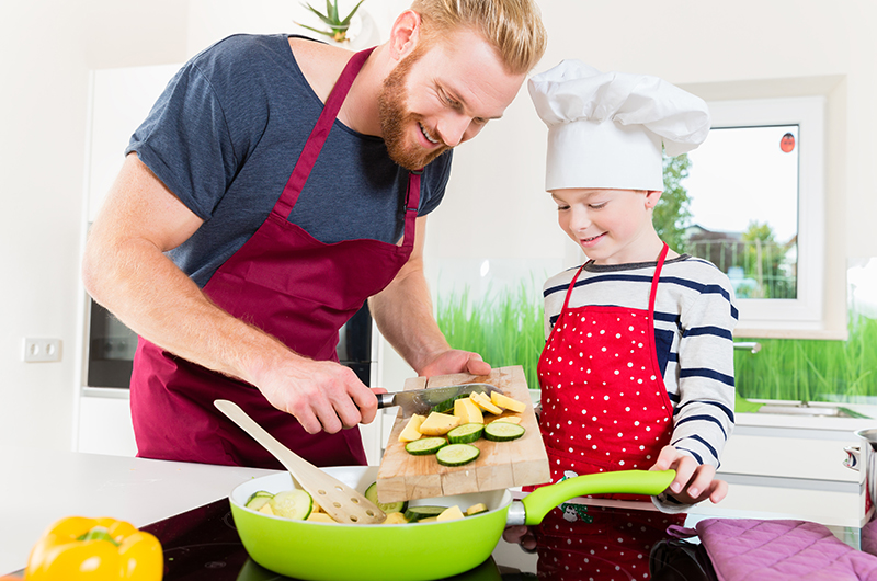 Father and son preparing food together in kitchen