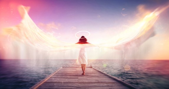 Female angel on a jetty overlooking the ocean