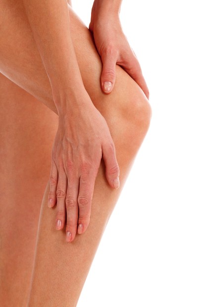 Closeup shot of woman holding sore knee, isolated on white backg