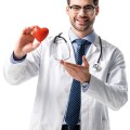 Smiling doctor wearing white coat with stethoscope and holding t