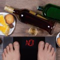 Male feet on digital scales and sign no surrounded by bottles an