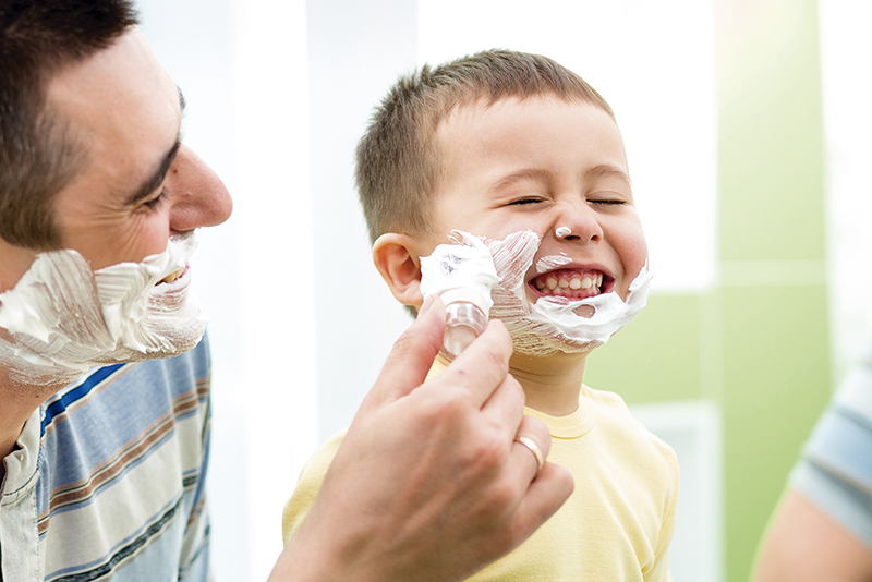 playful kid and father shaving together at home bathroom
